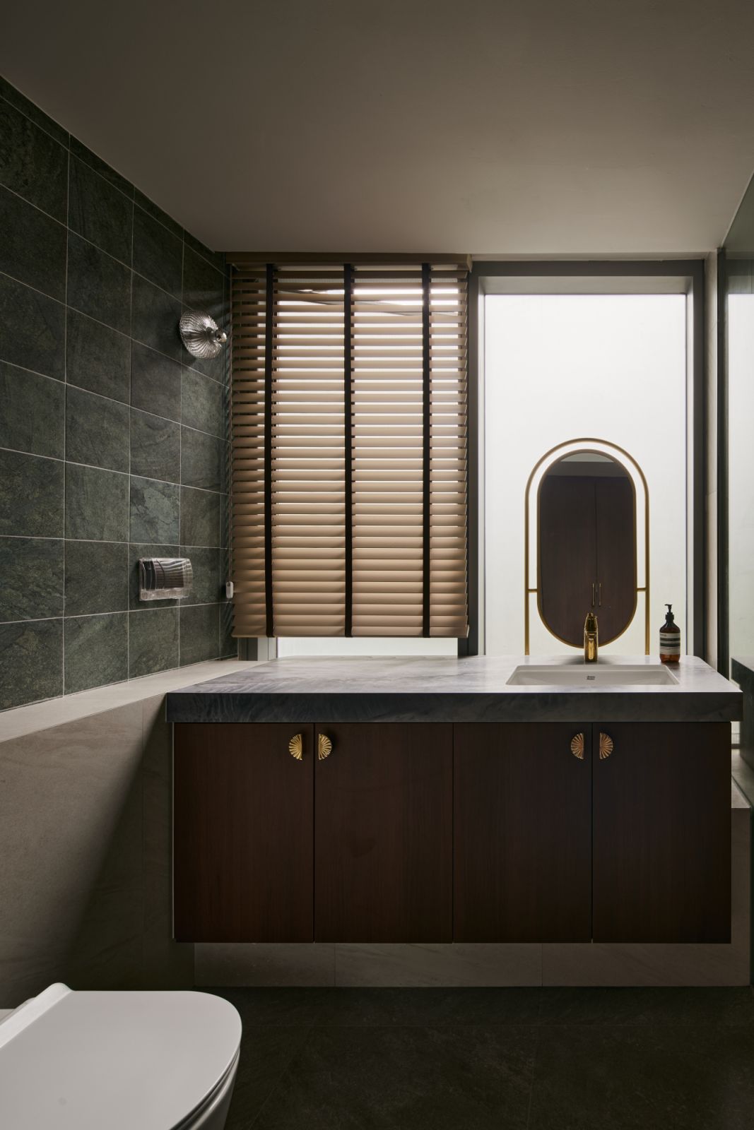 Brushed brass detailing and soft curves bring a sense of refinement to the secondary vanity, complemented by a view of the architectural courtyard lightwell