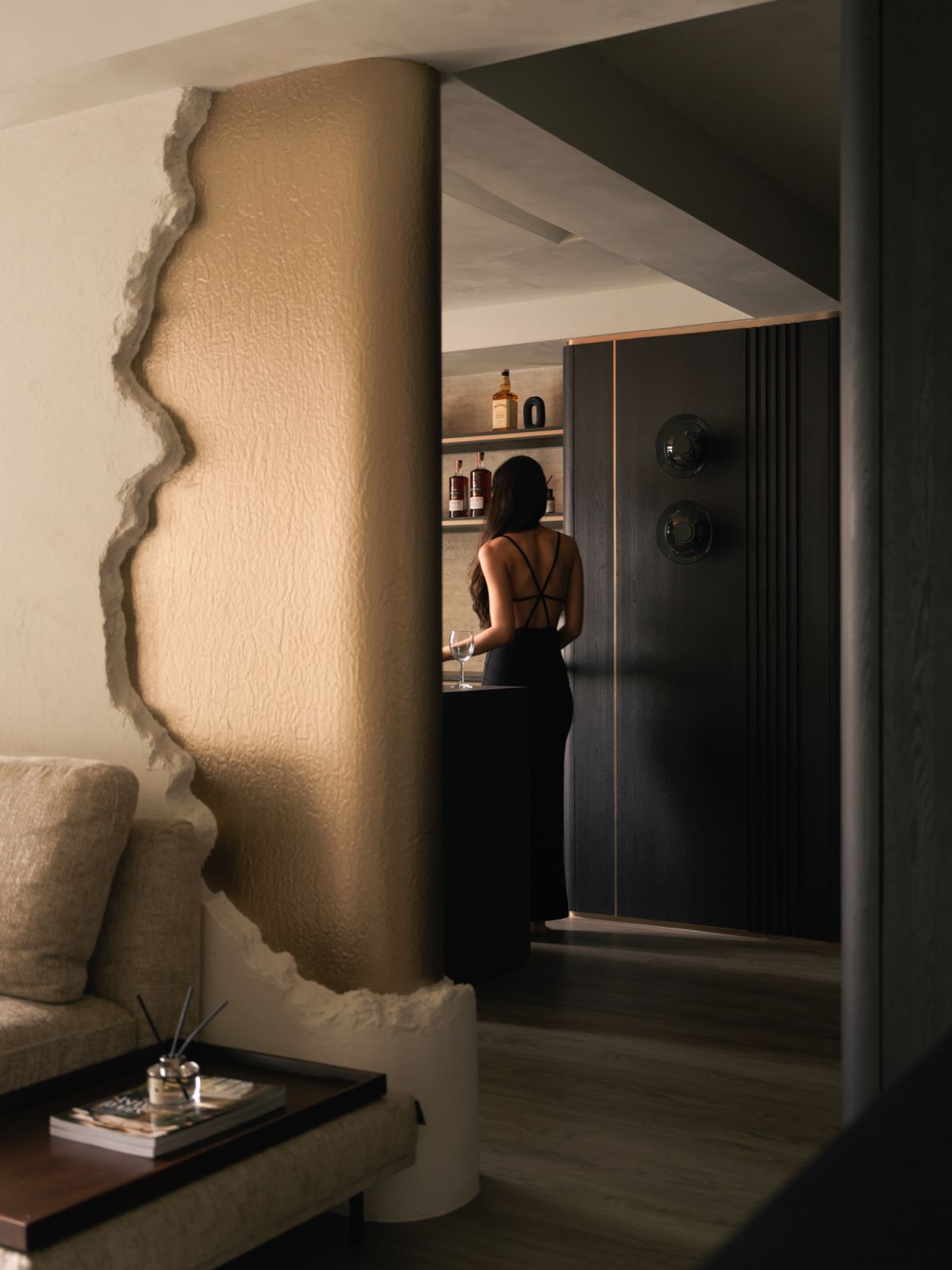 Textural interplay between raw and refined continues into the bar nook, tucked behind the column and clad in dark timber joinery