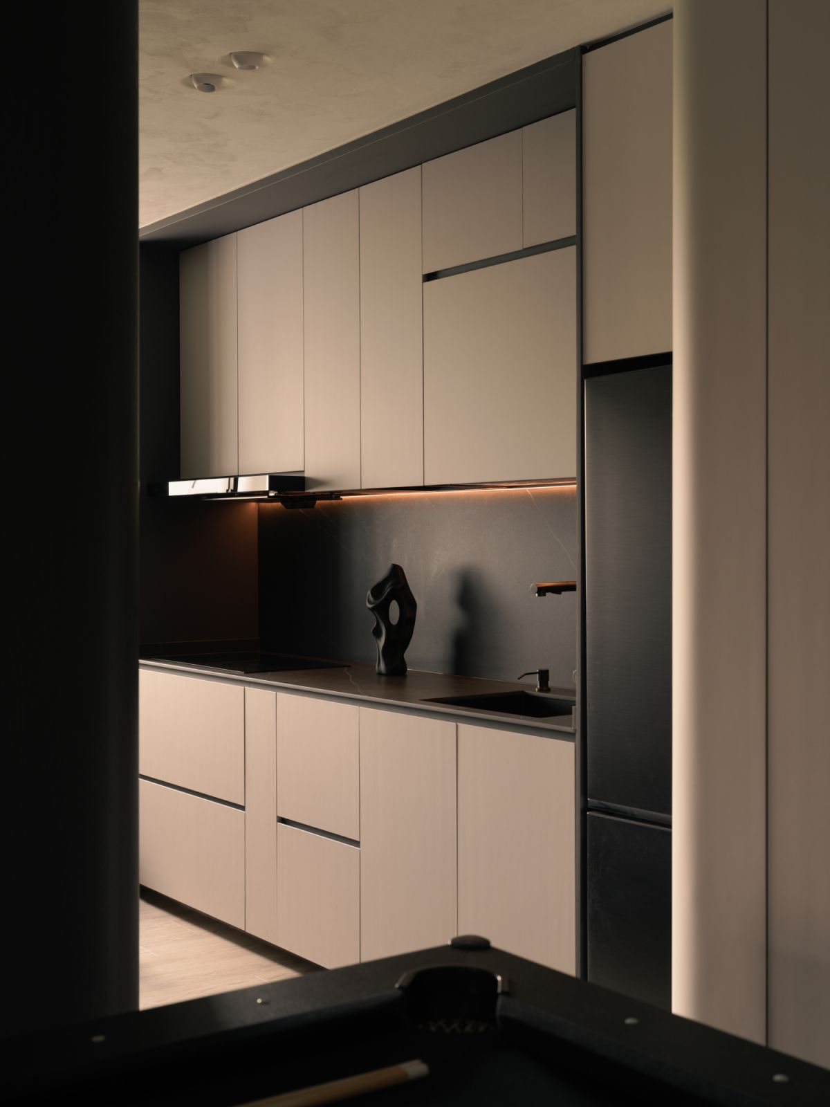The minimalist dry kitchen keeps to the home’s monochromatic scheme, with streamlined cabinetry, matte finishes and copper-toned accents