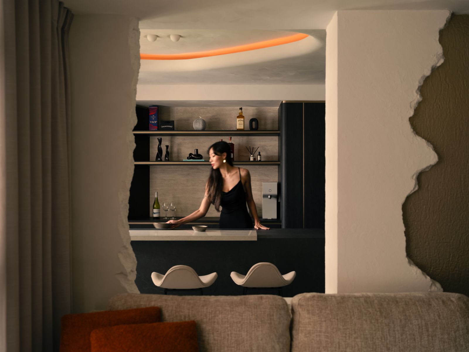 A sculpted archway frames the bar in theatrical fashion, revealing a curated mix of spirits, scents and sculptural accents