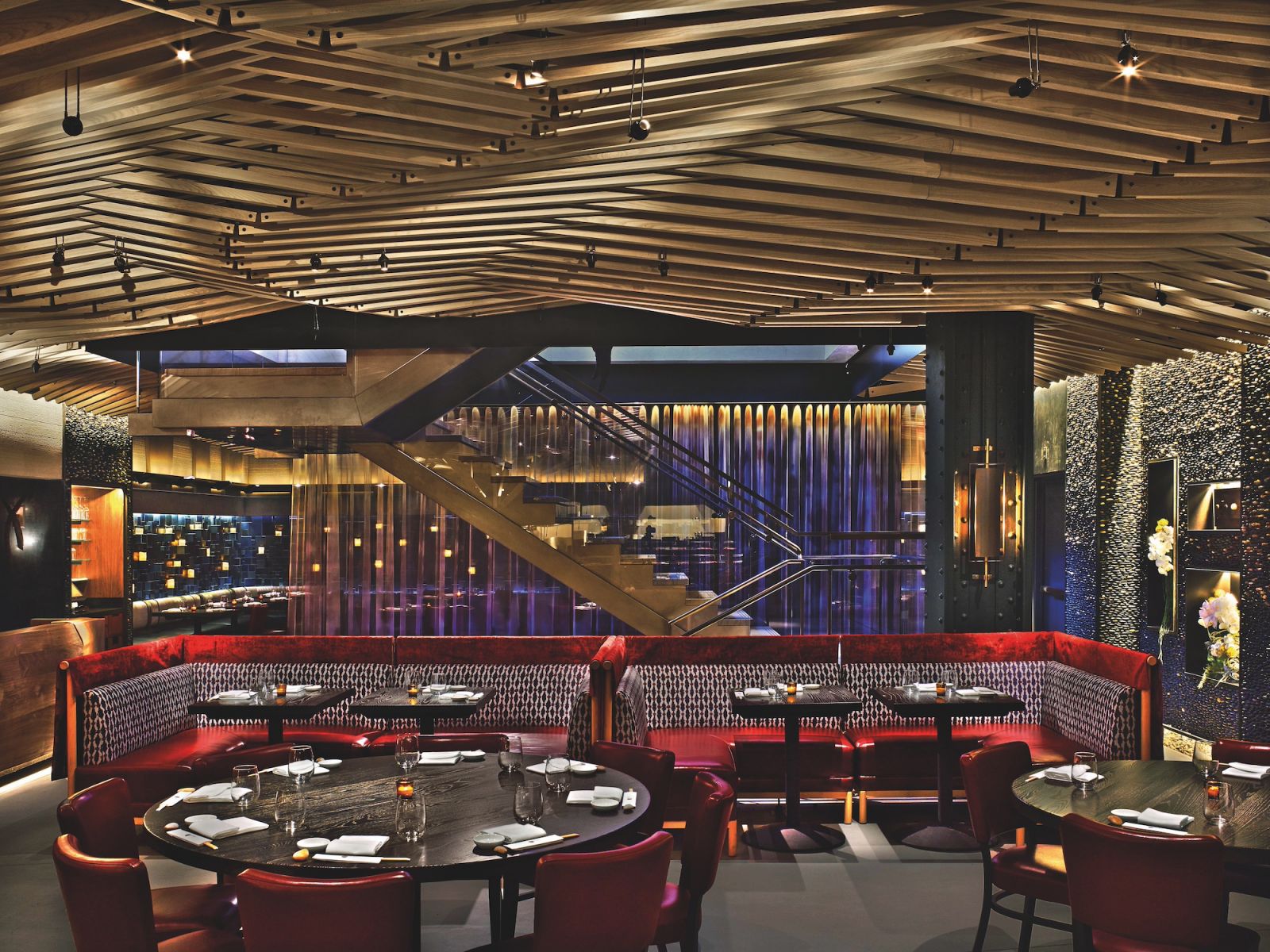 The main dining room in Nobu NYC Downtown features plush banquette seating with Japanese patterns in rich Peruvian colours and a river-rock wall by the staircase (Photo: Eric Laignel)