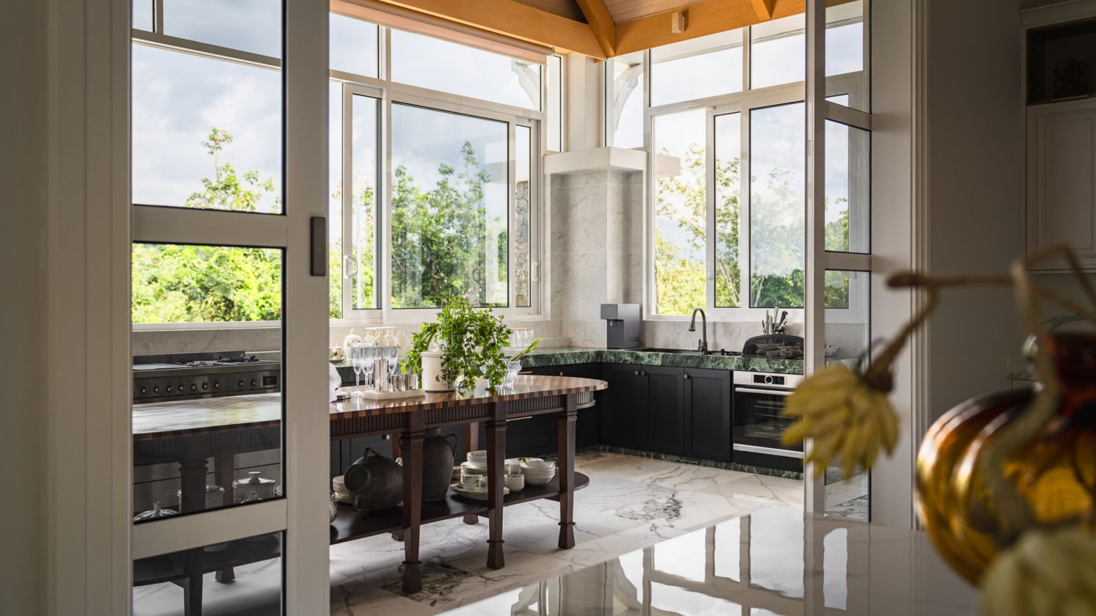 The kitchen is bathed in natural light from expansive windows that