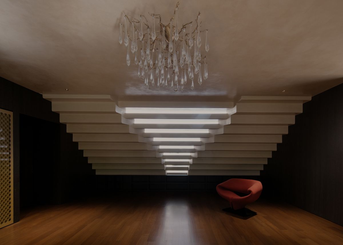 The library’s reading area features a biomorphic chandelier and moody illumination courtesy of the articulated architectural opening