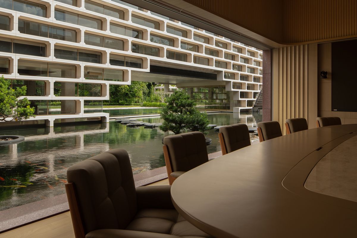 The conference room enjoys the scenic view via the openings and refreshing breeze thanks to the water feature