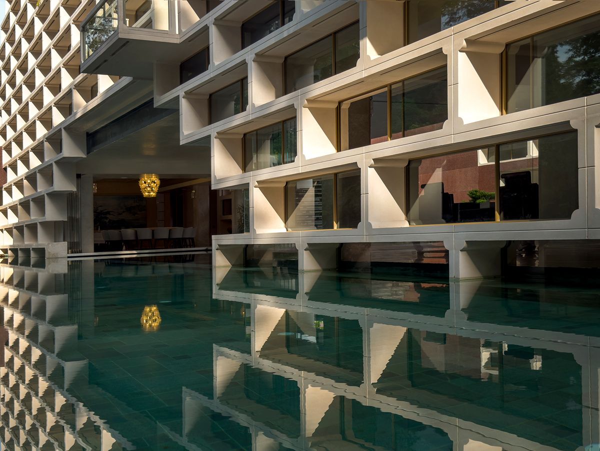 The living and dining spaces connected by a bridge over koi ponds on one side, and the pool on the other