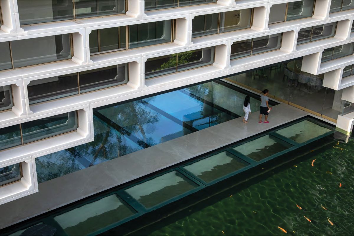 A walkway connecting the living and dining area flanked by pools through which one can spy the subterranean spaces below