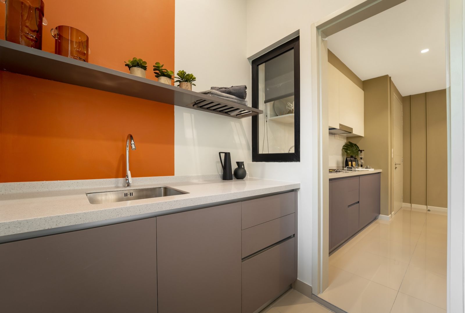 The kitchen's wet area showcases the unit’s strategic use of orange accents through the vibrant backsplash, which creates visual depth and warmth