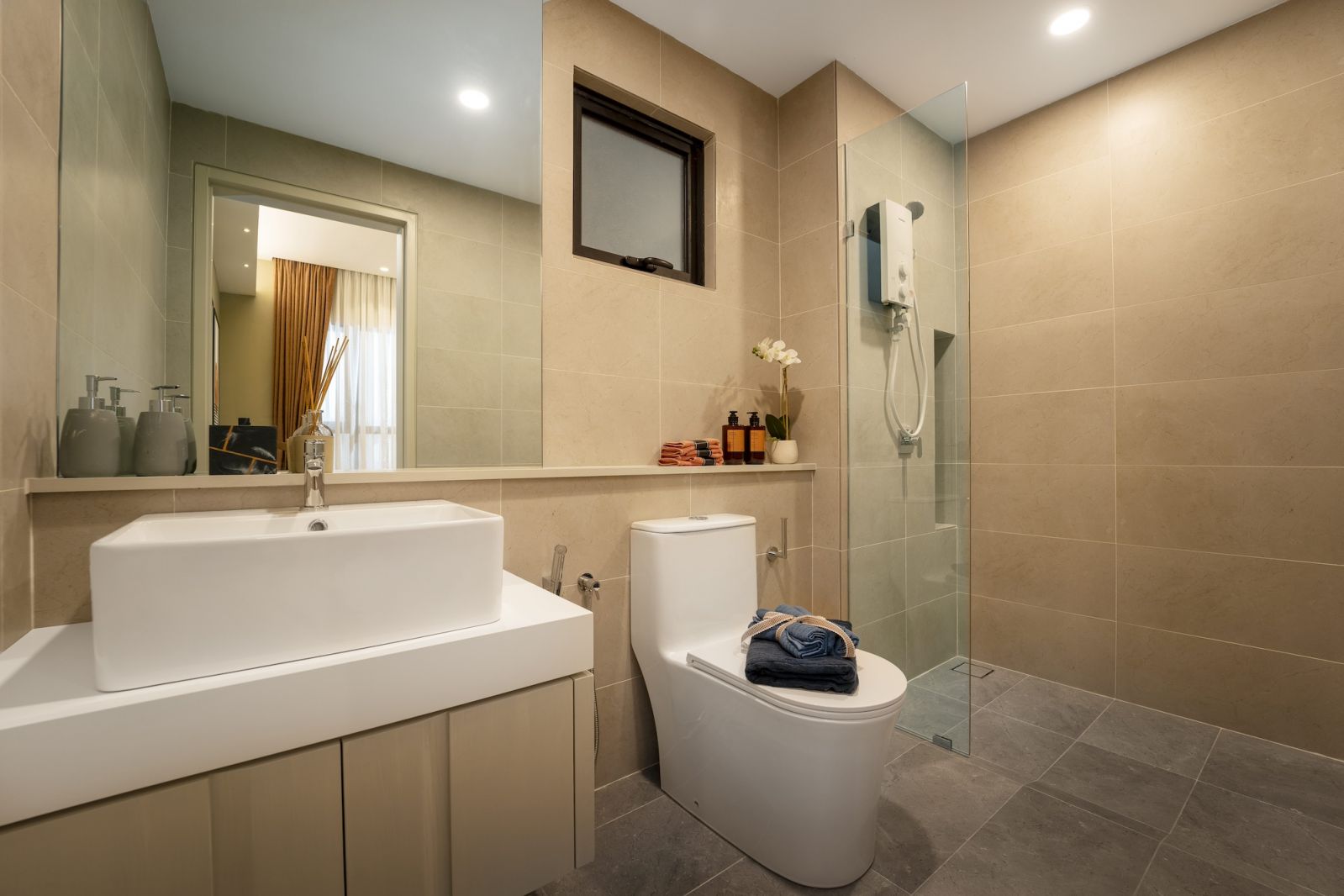 The bathroom continues the unit’s material palette with neutral tones and clean lines that prioritise function while maintaining visual continuity with the living spaces
