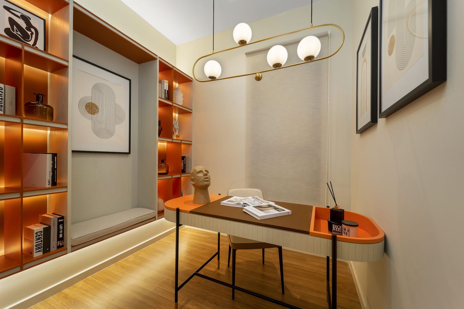 The home office demonstrates the unit’s versatility through orange-backed shelving and brass pendant lighting, exemplifying how the signature colour accent connects different areas