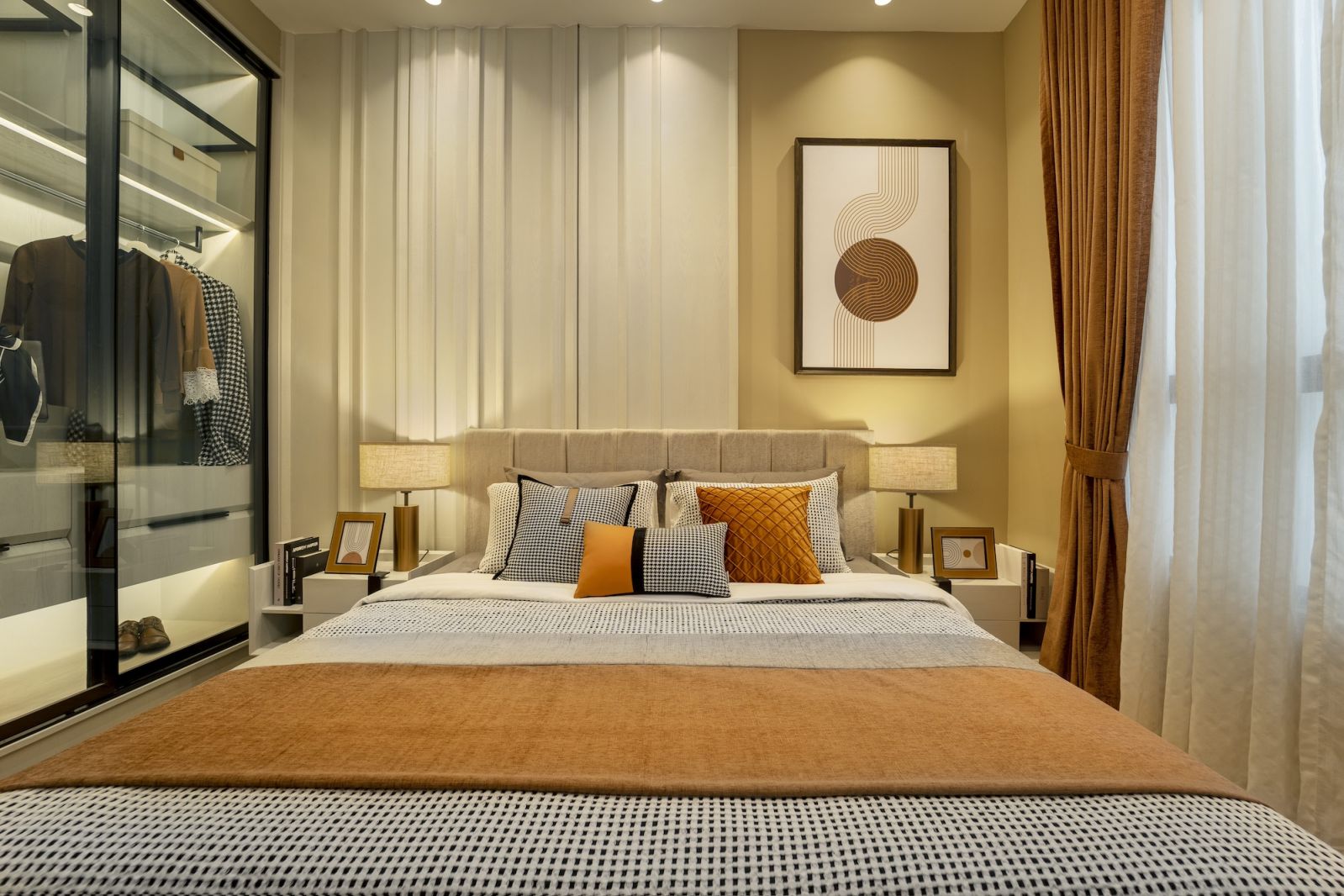 The master bedroom emphasises the unit’s sophisticated material palette through textured panelling and brass pendant lights