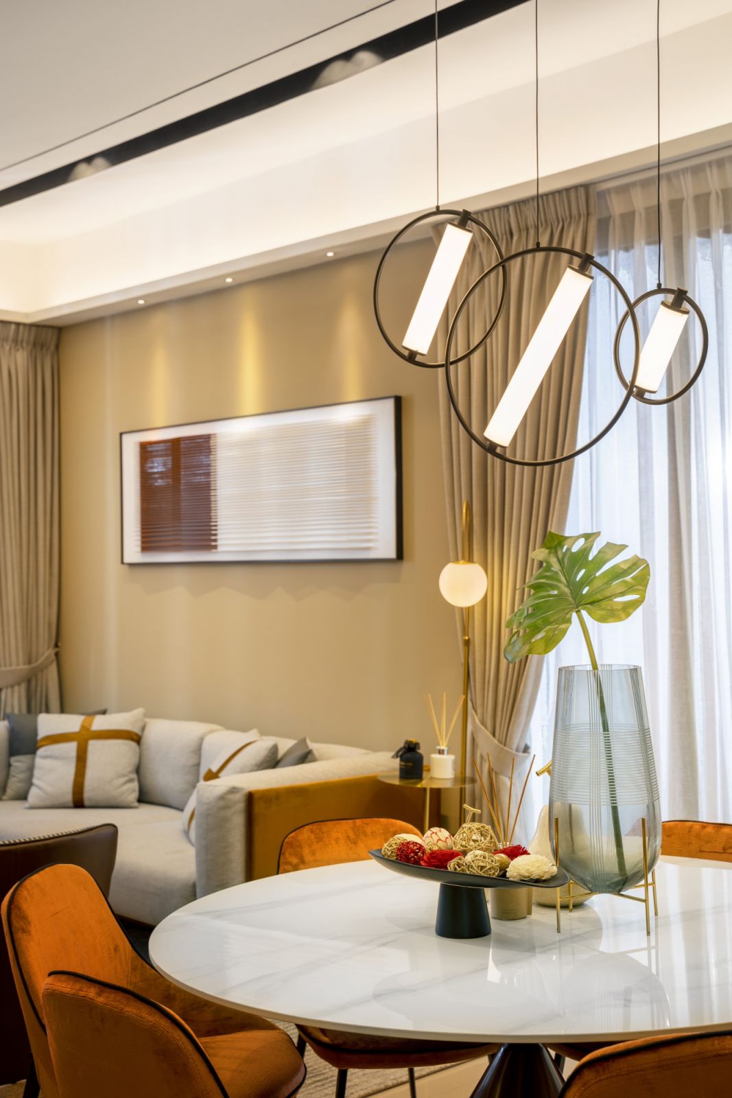 The dining area’s sculptural pendant lighting and orange upholstered chairs demonstrate the unit's approach to creating visual interest through strategic accent placement