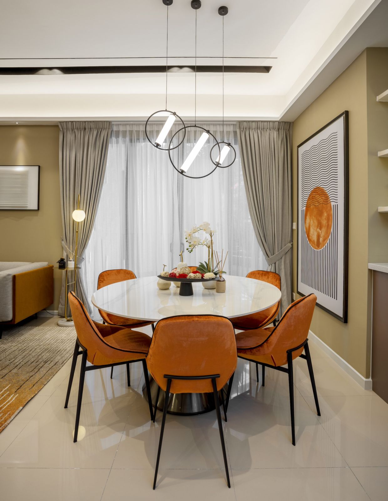A closer view of the dining area reveals how the circular pendant lights and orange chair upholstery create a visual rhythm throughout the space