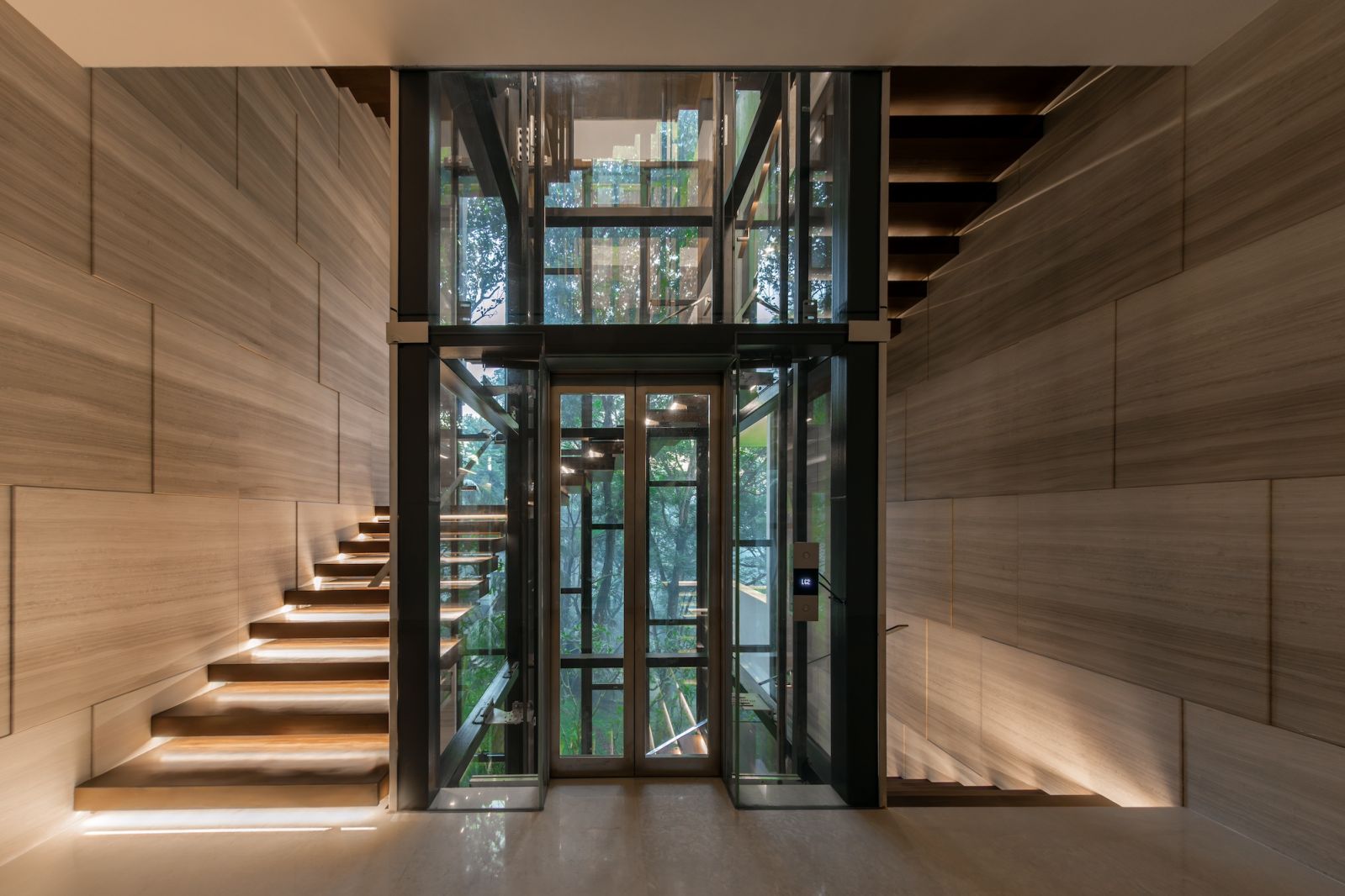 The floating open-riser staircase wraps gracefully around a glass lift, serving as both a sculptural centrepiece and a thoughtful accessibility feature