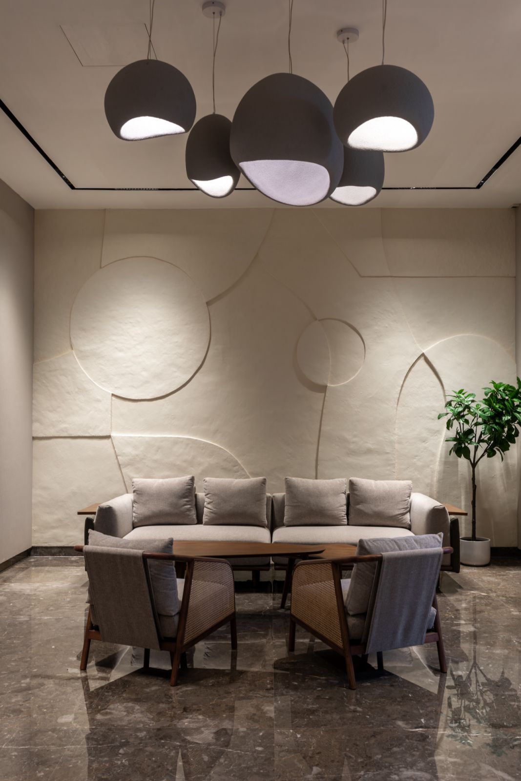 An intimate conversation corner where a cluster of pendant lights cascade from above, casting a warm glow against the light-colored stone wall