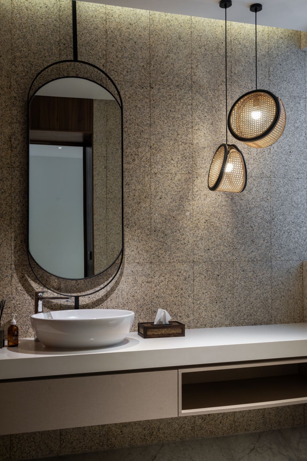A luxurious bathroom showcases the refined material palette with granite feature walls, contemporary fixtures and woven pendant lights