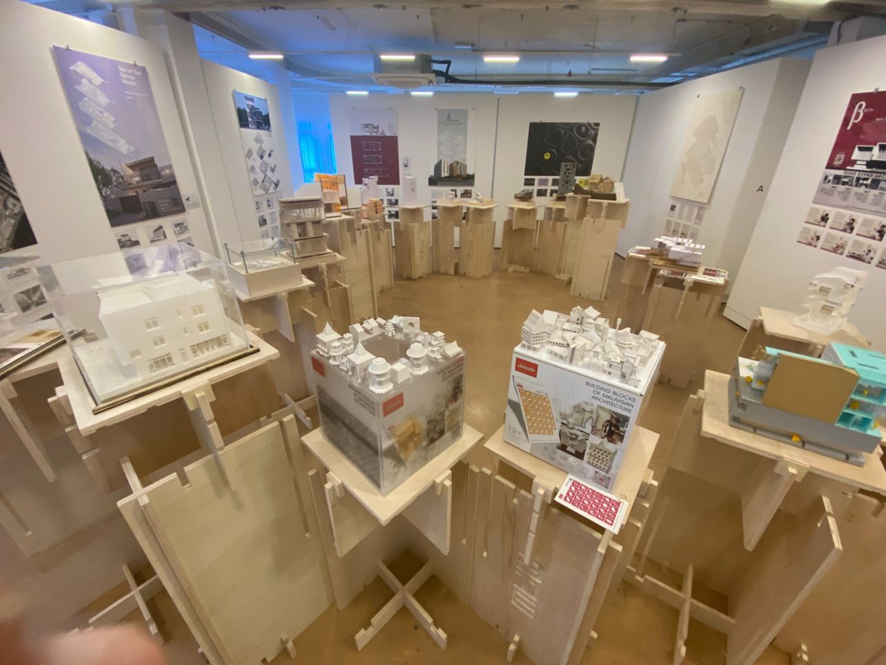 The Malaysian Architecture Week 2025 exhibition displays sectional models on wooden stands, demonstrating the organisers’ approach of slicing through silence to reveal hidden architectural narratives through cuts in the models.