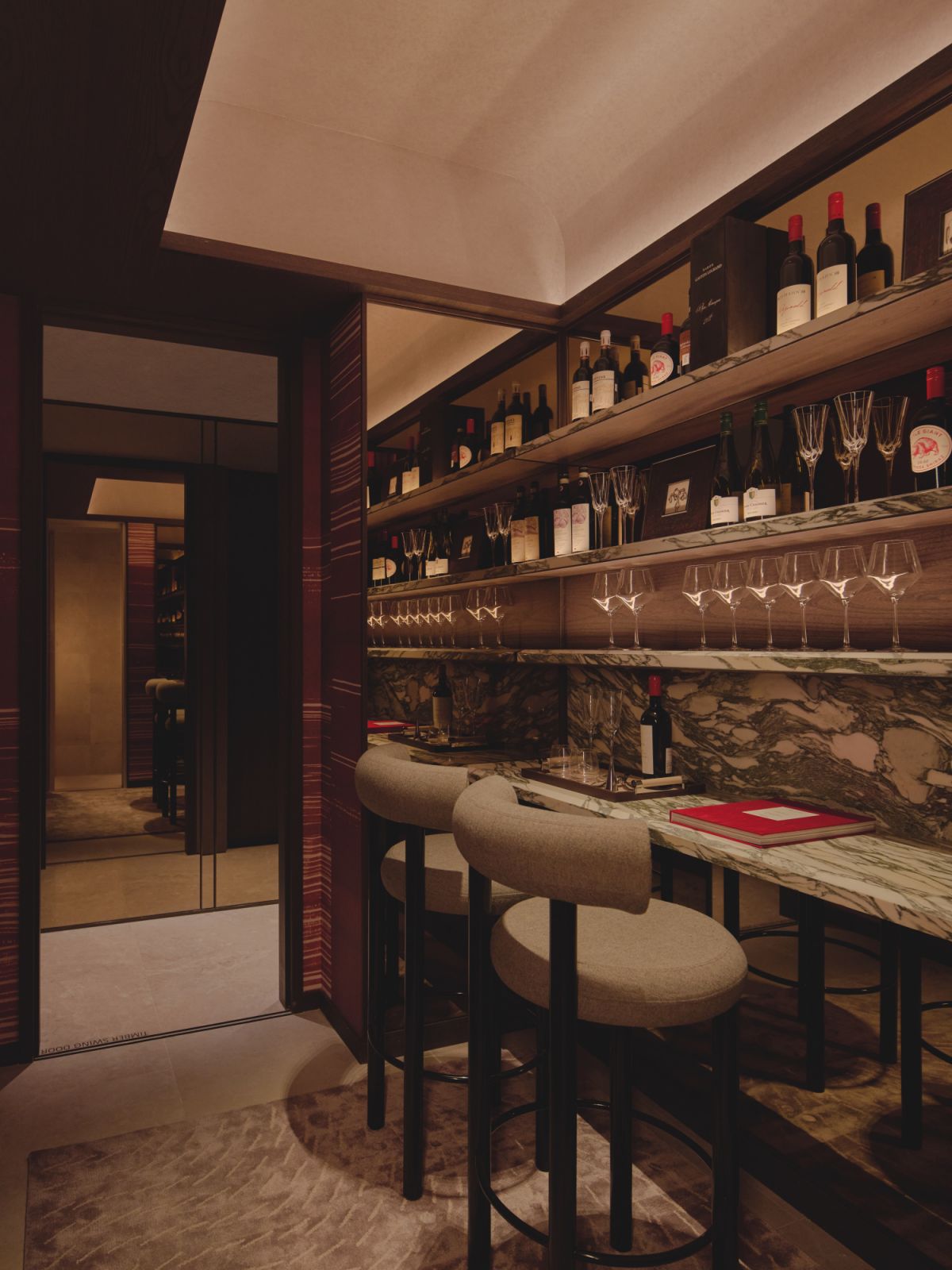 A richly veined stone countertop evokes the decadence of an upscale lounge, forming the centrepiece of a bespoke bar nook dressed in deep, sophisticated tones