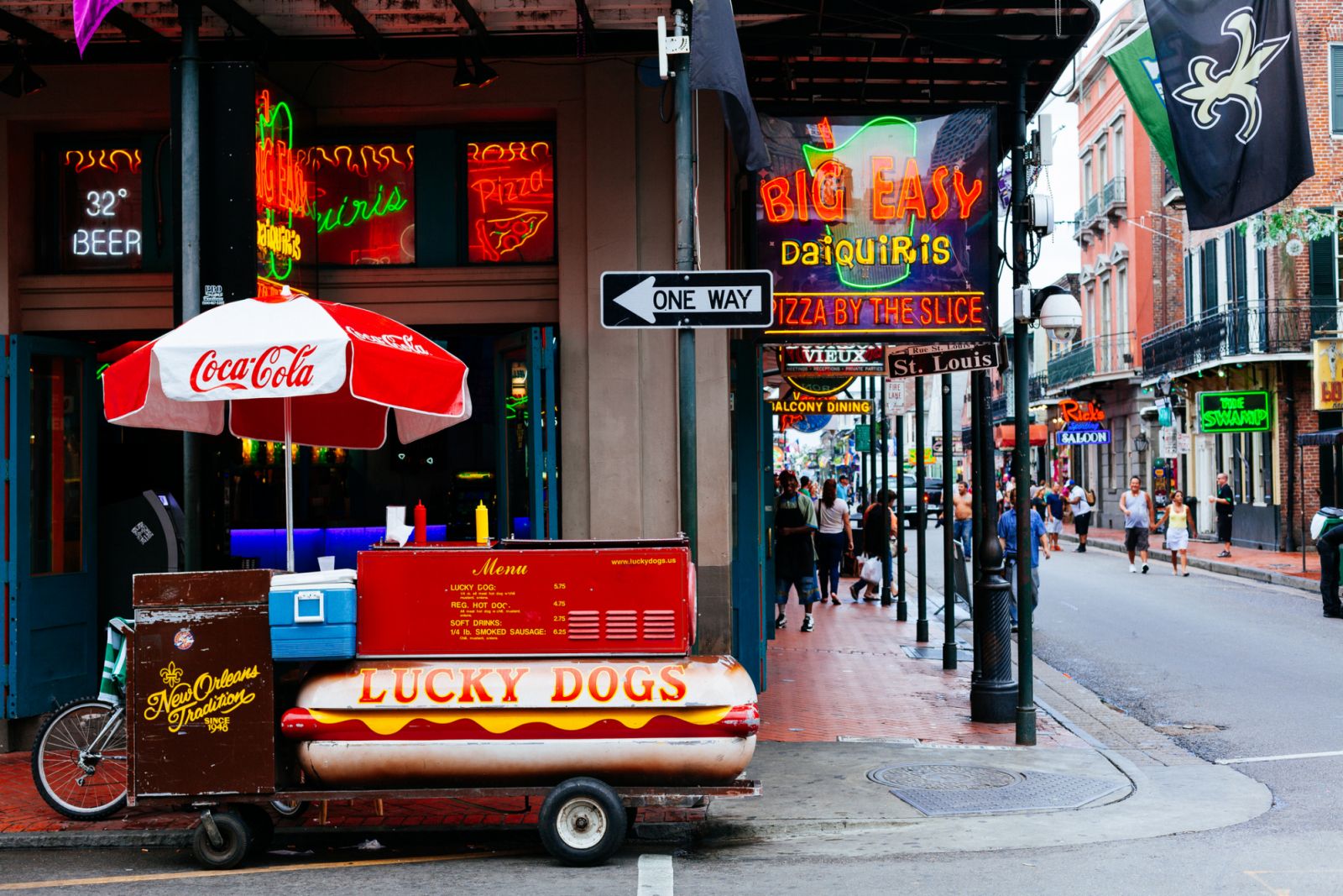 New Orleans - August 14, 2013: Food Stand selling hot dogs in Bourbon Street, several pubs and bars along the road and people walking around in the background. Bourbon Street is a street in the heart of New Orleans' oldest neighborhood.