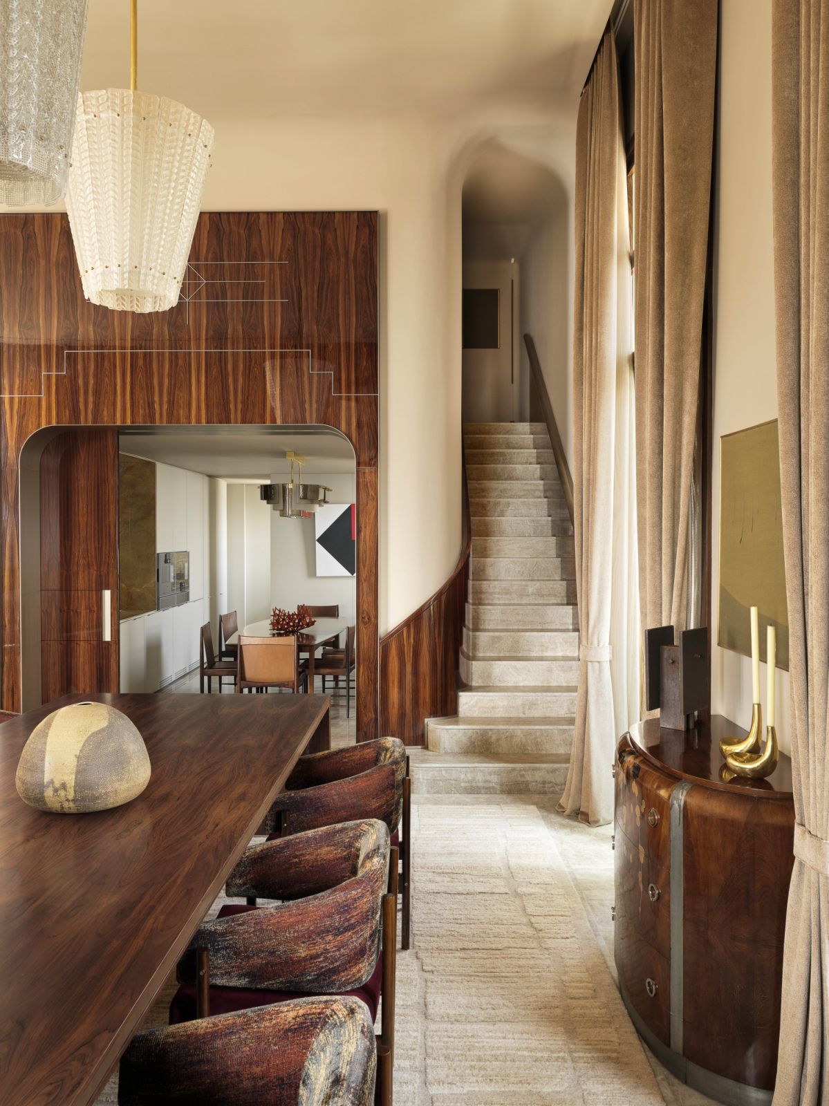 In the dining area, a jacaranda wood table by Meire Gomide is topped with a Terra ceramic piece by Shoko Suzuki from Gomide&Co, while a cabinet by Michel Dufet features a sculpture by Raul Mourão from Carbono Gallery and bronze candleholders by Lucas Recchia