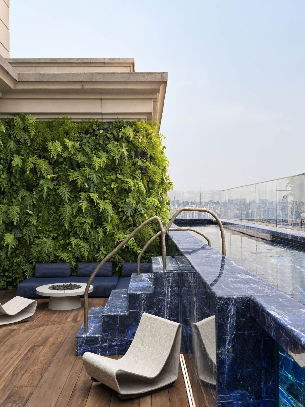 On the second-floor terrace, a pool lined with deep-blue Sodalite stone sets the tone for a serene outdoor lounge with vintage concrete chairs by Willy Guhl