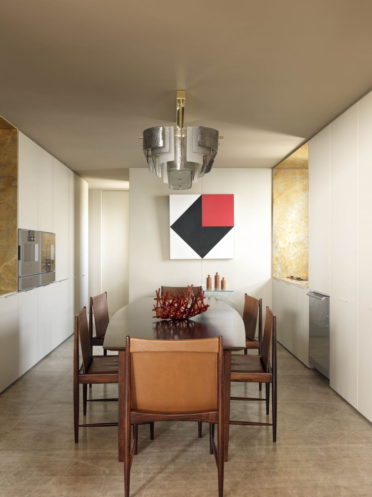 The kitchen features a 1950s caviuna wood table by Forma, paired with the Cantu Alta chairs by Sergio Rodrigues, an Italian art deco chandelier and the Ninho vase by Lucas Recchia