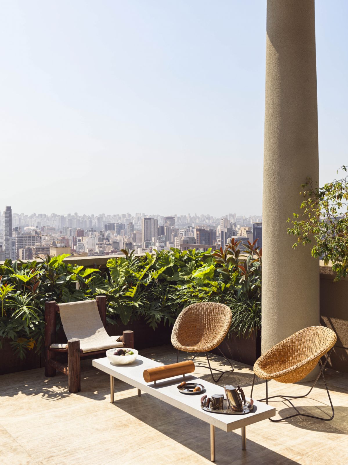 On the terrace, chairs by Carlo Hauner and Martin Eisler, a raw-wood chair from Apartamento 61 and a bench by Claudia Moreira Salles accompany a 1960s silver-plated and rosewood coffee table by Aurea from Bossa Gallery