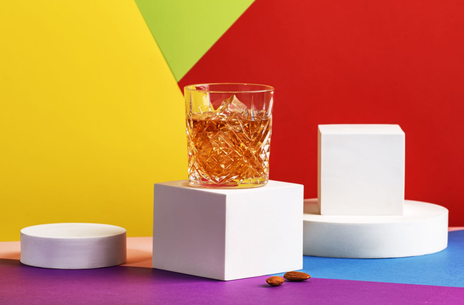 French connection alcoholic cocktail with cognac and amaretto liqueur. Modern style still life on fashionable multicolored background