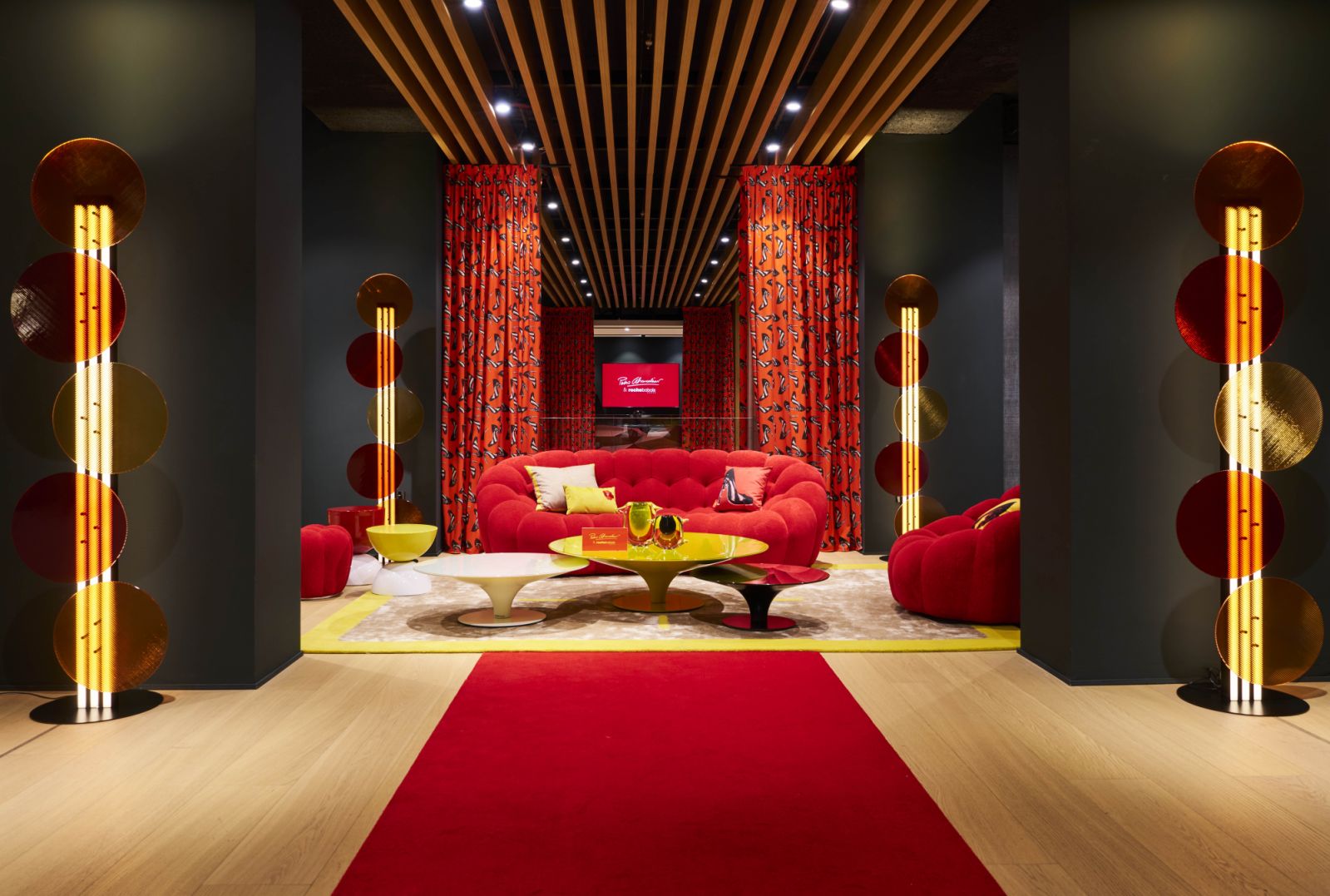 A majestic, symmetrical showcase dressed in red anchors the Roche Bobois showroom with theatrical flair