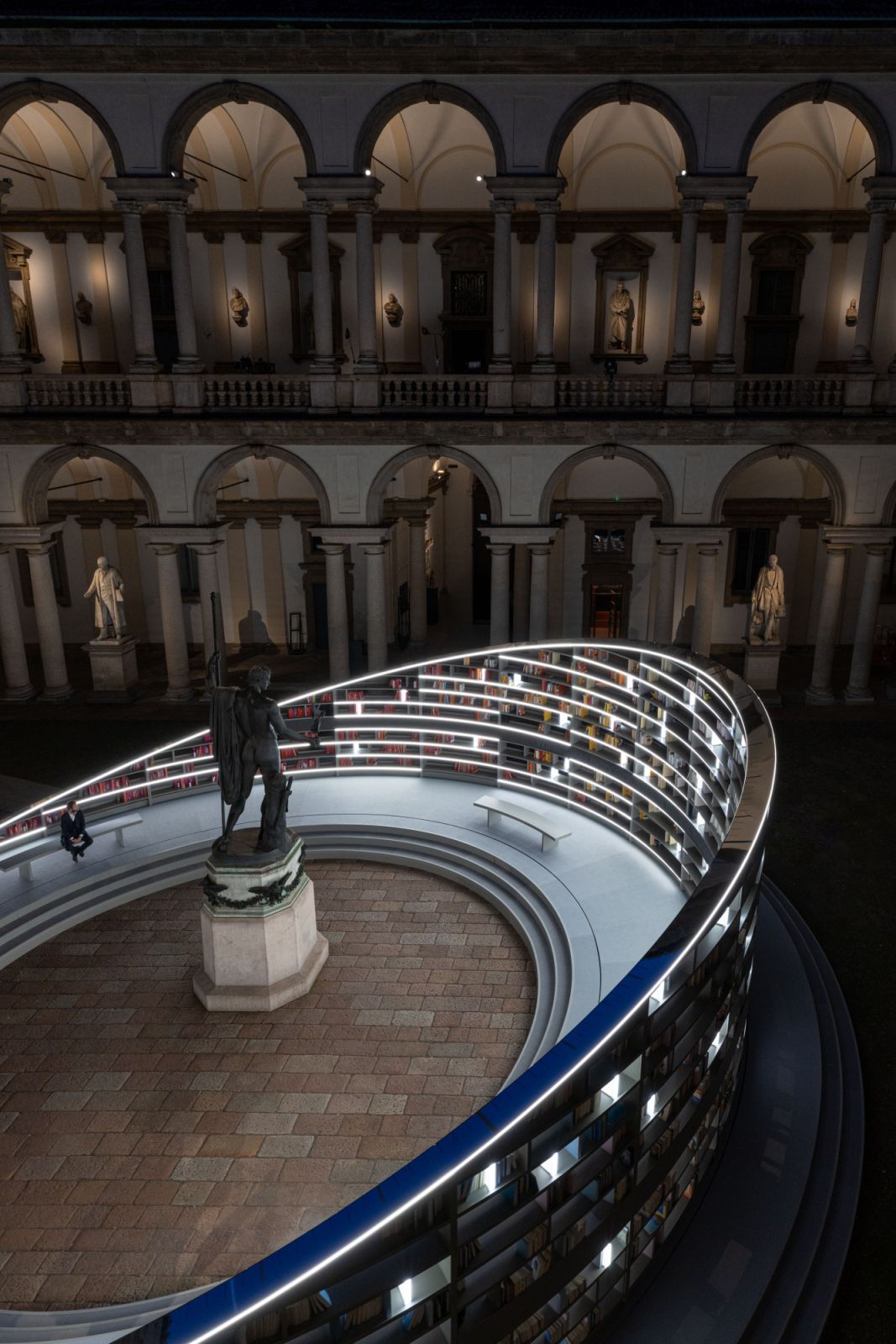 The installation takes centre stage in the ancient courtyard, casting shifting light across the storied walls of the Pinacoteca di Brera