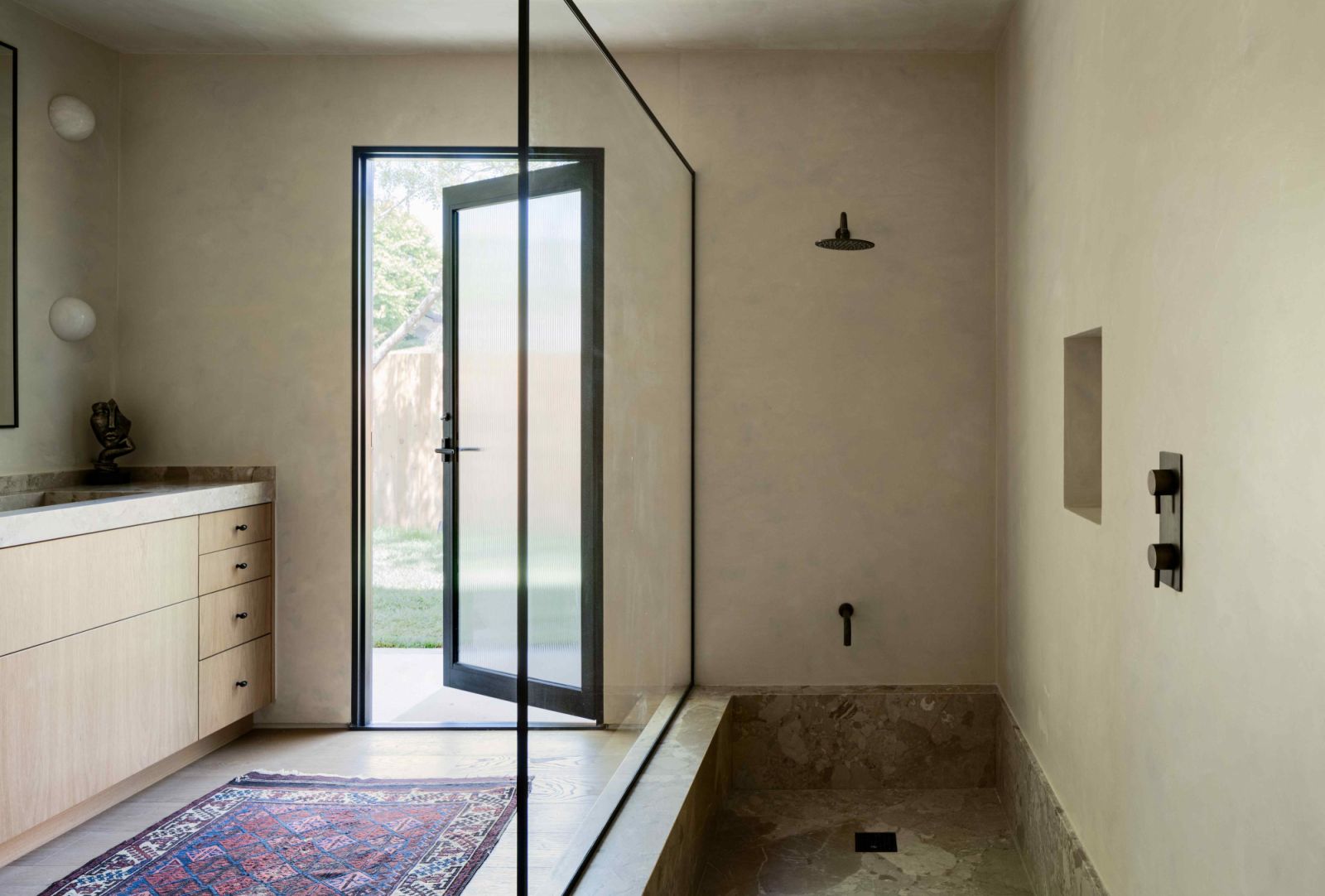 The sunken shower in the primary bathroom adorned with soft Ceppo marble