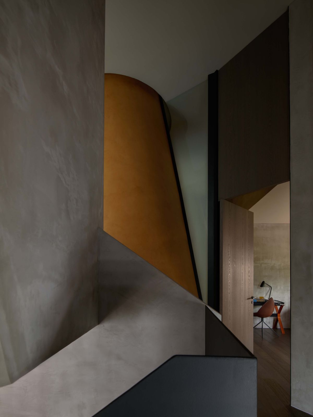 A sculptural stairwell frames the ochre mineral-painted walls surrounding the oculus, offering one of the few accents of colour in the otherwise monochrome 3D-printed house