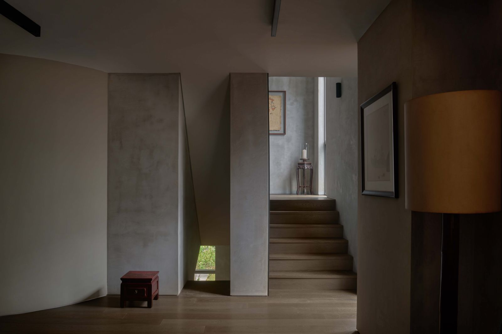 Natural light filters through a narrow opening beside the stairs, softly illuminating the 3D-printed walls and articulating the quiet spatial rhythm of the upper levels