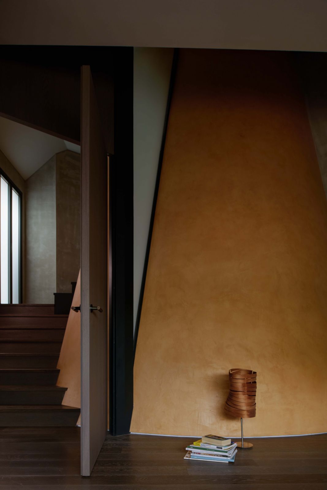 Ochre mineral-painted walls mark the sculptural centre of the home, contrasting the cool concrete palette and signalling the presence of the oculus beyond