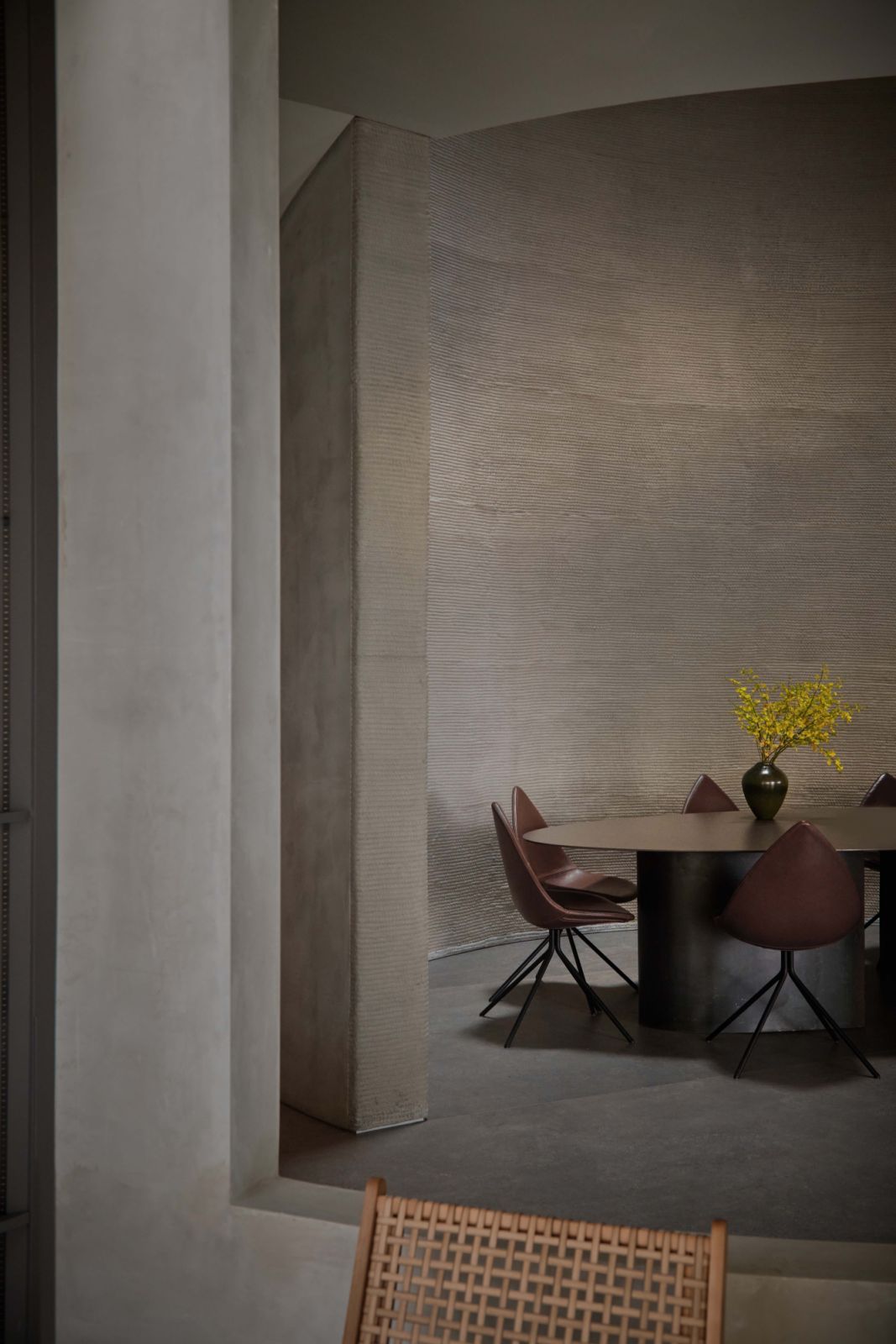 The dining area sits beneath the six-metre-high oculus, framed by raw 3D-printed concrete walls whose rhythmic texture celebrates the layered precision of additive construction