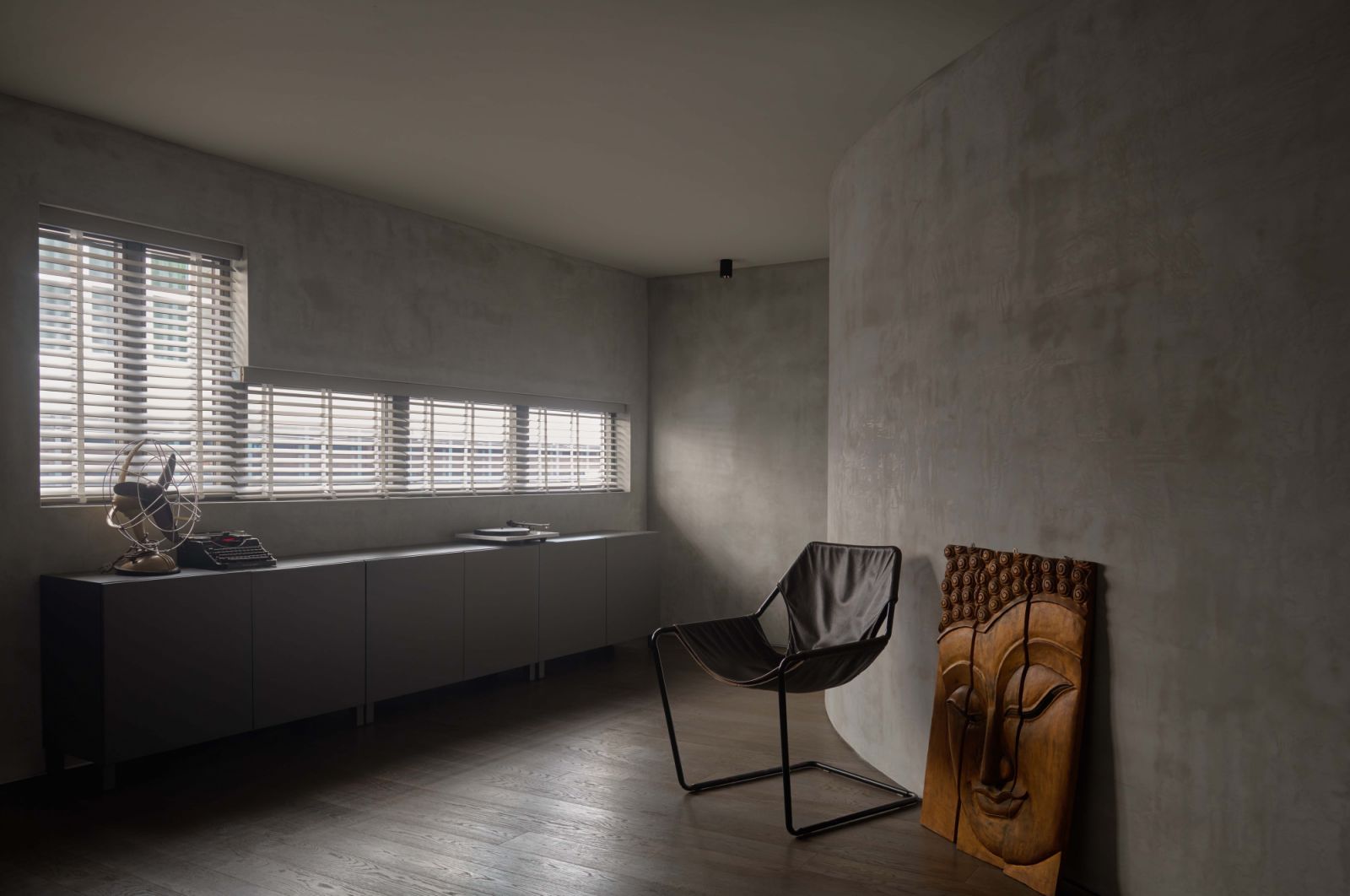 A reading nook features curved 3D-printed concrete walls left bare, highlighting the home’s raw materiality and the interplay of light across its textured surface