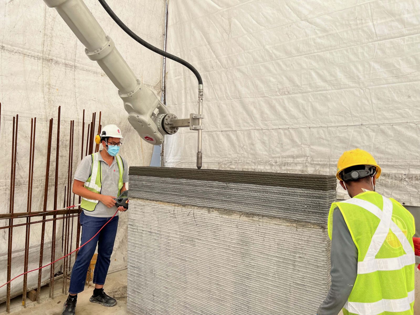 A robotic arm from CES_InnovFab extrudes layers of concrete on-site, forming structural walls with minimal manpower—highlighting one of the key innovations behind Singapore’s first 3D-printed house