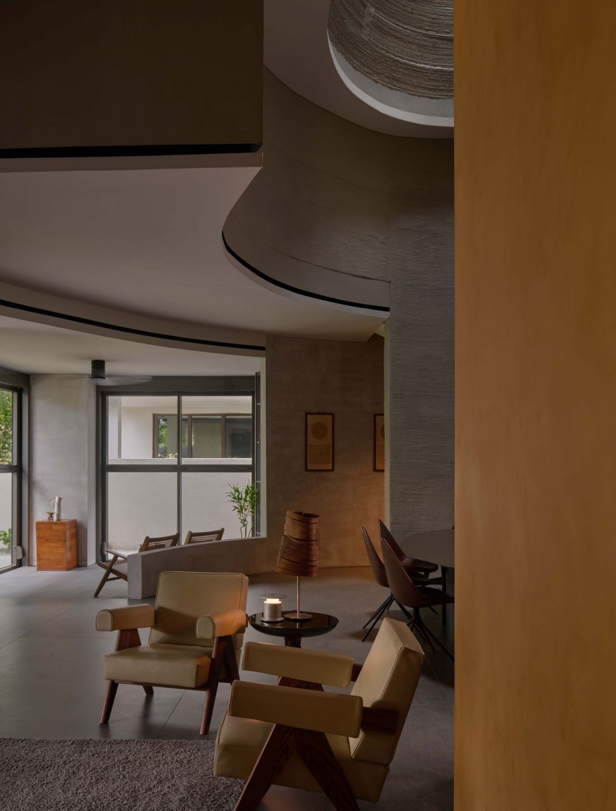 The living area flows into the dining space beneath the oculus, revealing how curves, light and layered materiality guide the experience within the 3D-printed home