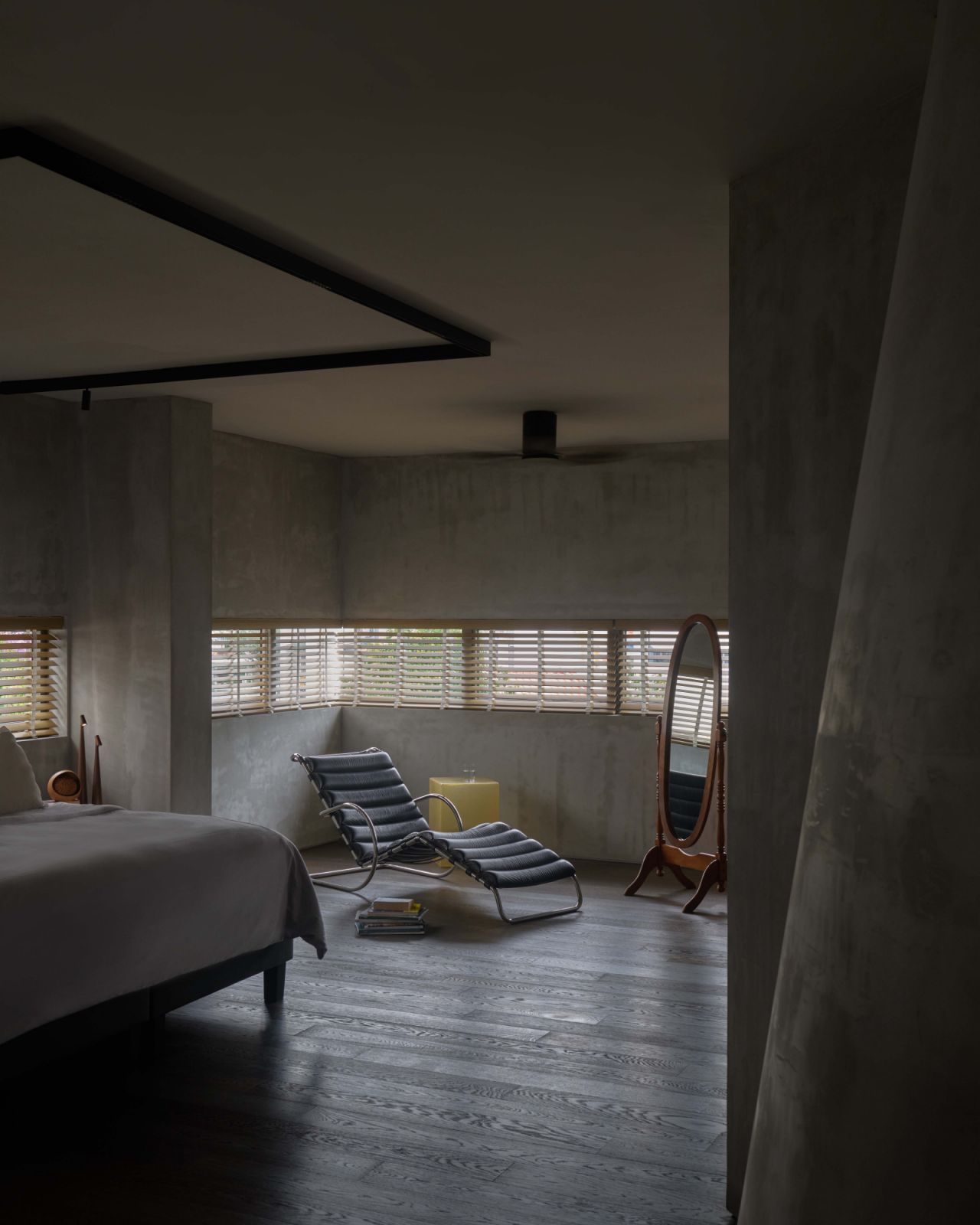 In the master bedroom, a corner window wraps the space with daylight while muted materials and curved 3D-printed surfaces maintain the house’s quiet spatial language