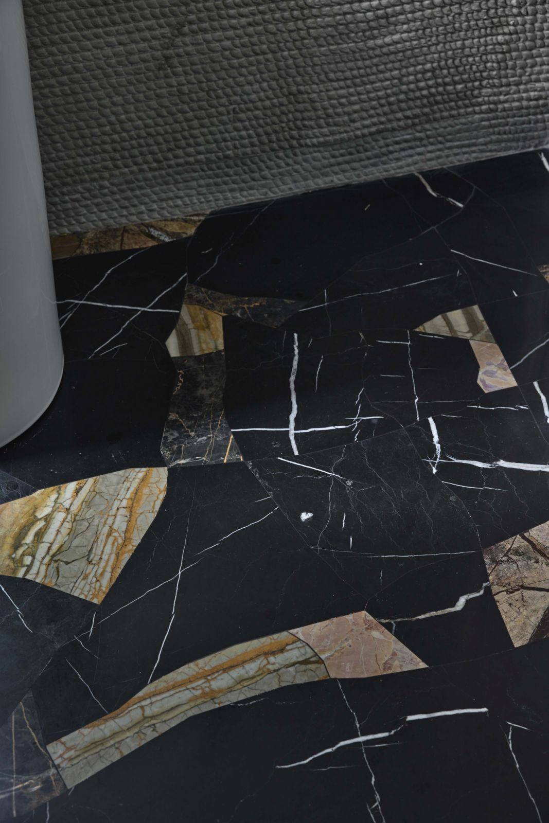 In the powder room, offcut marble fragments were repurposed into a patchwork floor finish, paired with textured 3D-printed walls to highlight material reuse and contrast