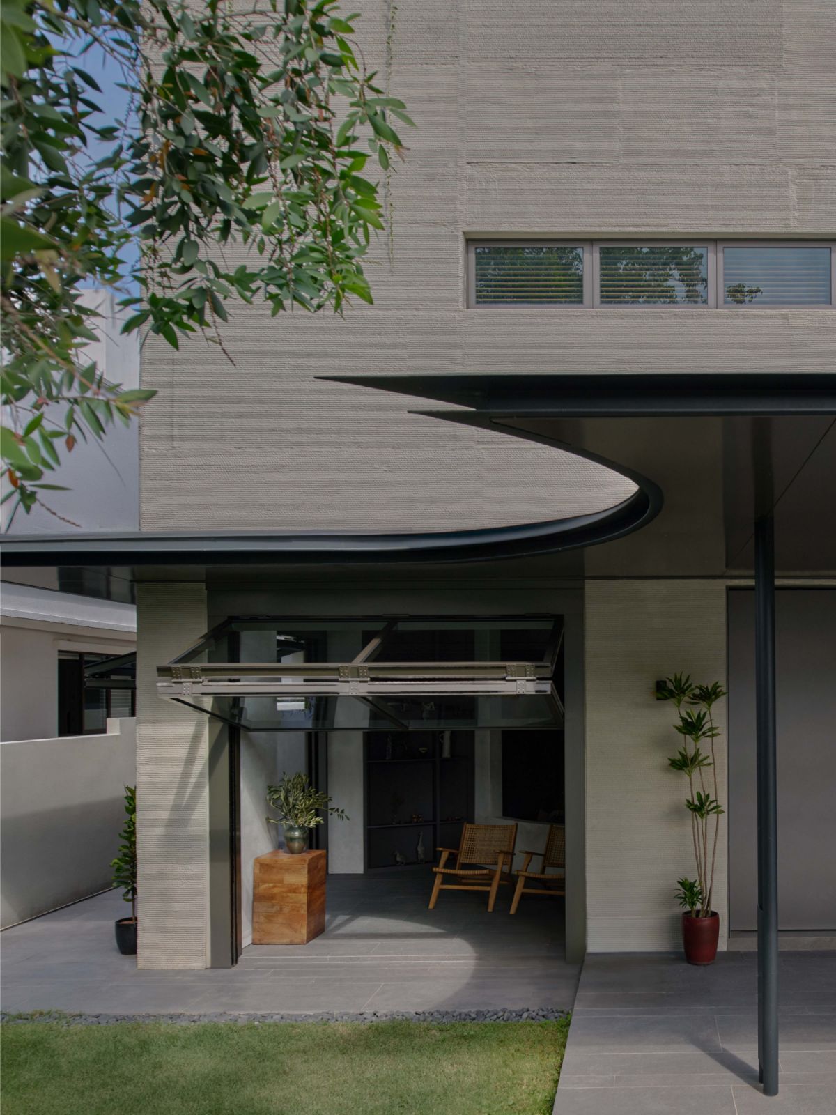 A curved canopy and layered striations across the 3D-printed façade signal the home’s material honesty and construction innovation from the street-facing elevation