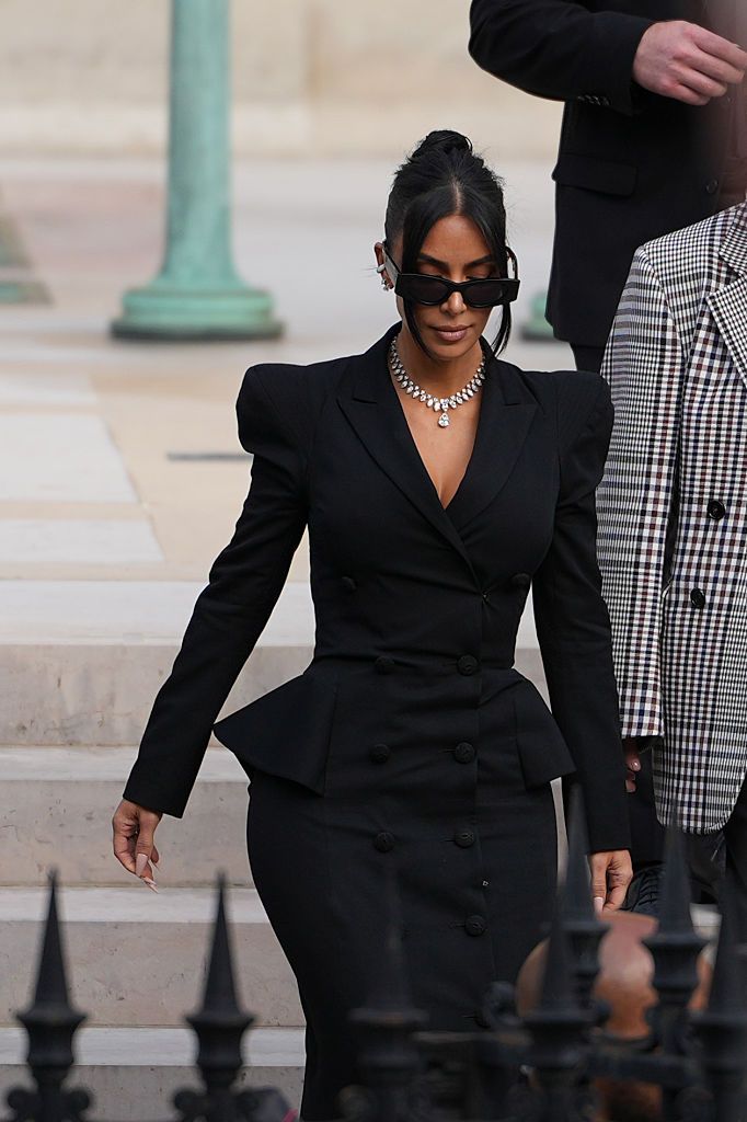 PARIS, FRANCE - MAY 13: Kim Kardashian exits the trial at the Palais de Justice, and wears sunglasses by Alaia, a black dress designed as a double breasted gathered blazer jacket with power shoulders / shoulder pads / puff shoulders and low-neck by John Galliano, a necklace by Samer Halimeh, Repossi diamond earcuffs, Brioni Raymond earrings, at the Palais de Justice, on May 13, 2025 in Paris, France. (Photo by Edward Berthelot/GC Images)