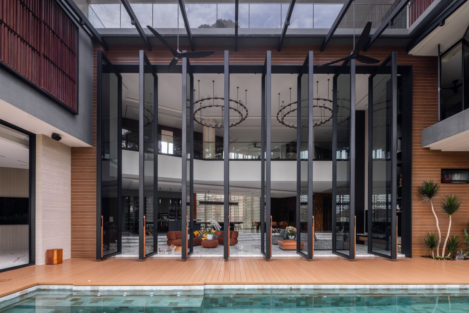 Full-length 7.3-metre pivot doors seamlessly connect the open-plan living area with the lush pool landscape