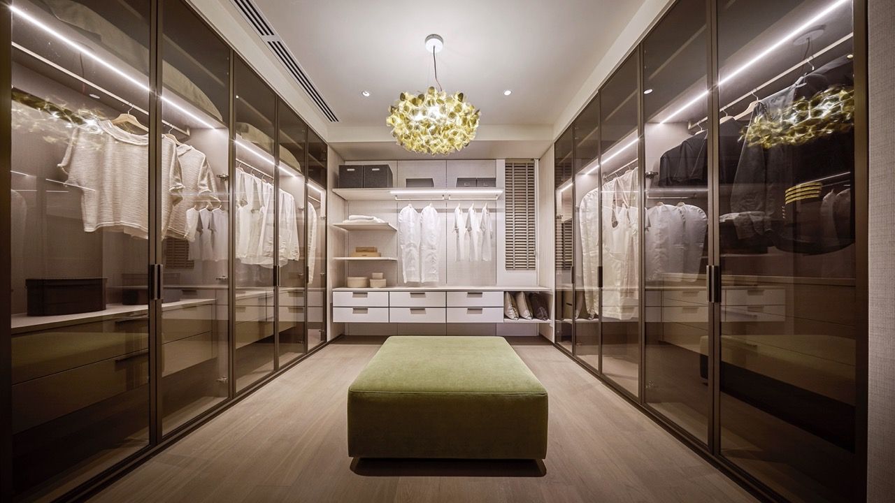 Walk-in wardrobe area with glass-fronted storage and central seating, part of the master bedroom suite configuration