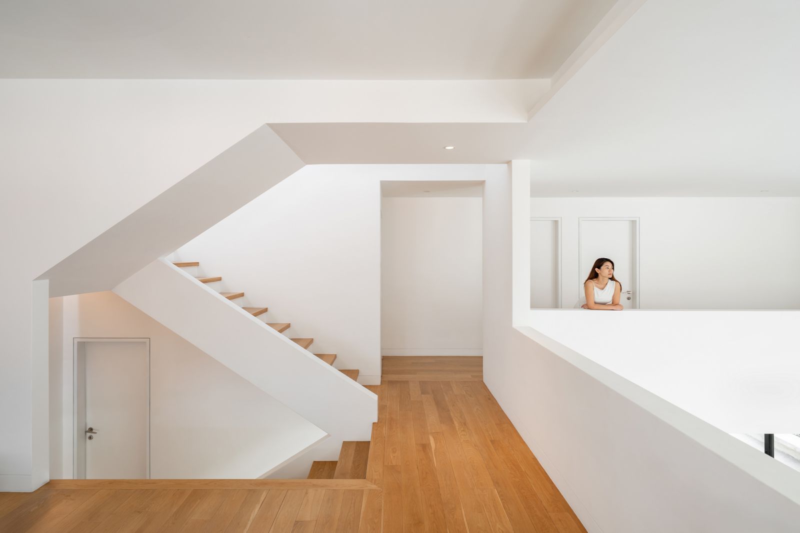 Upper-level family room in this Malaysian bungalow renovation overlooks double-height living spaces with oak timber flooring and connection to outdoor terraces