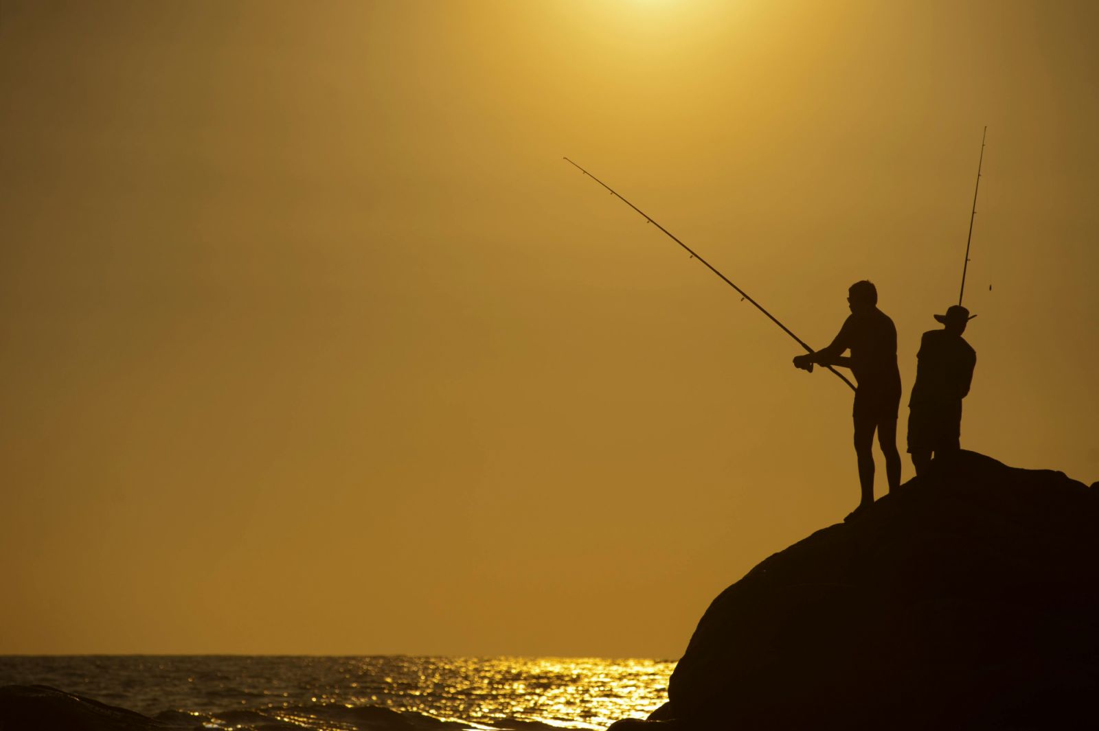 Two men fishing on top of a rock (Photo: Pexels/Alex P)
