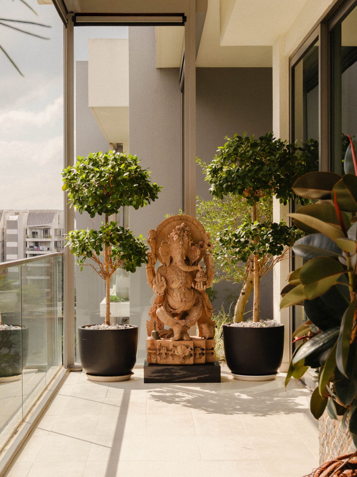 The balcony is adorned with plants and a statue of Ganesha