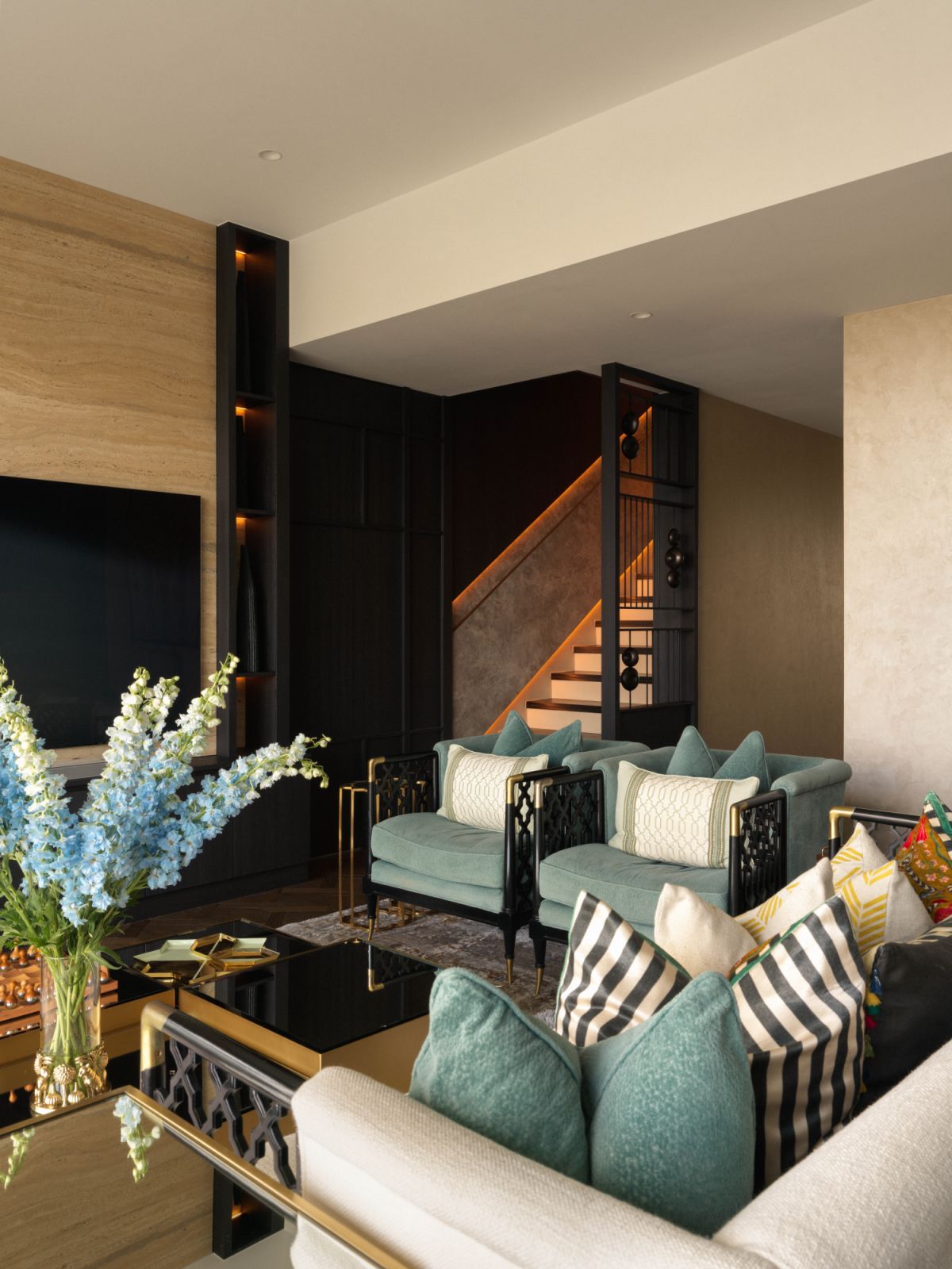 The living room’s medley of patterns and textures complements the dark-finish staircase