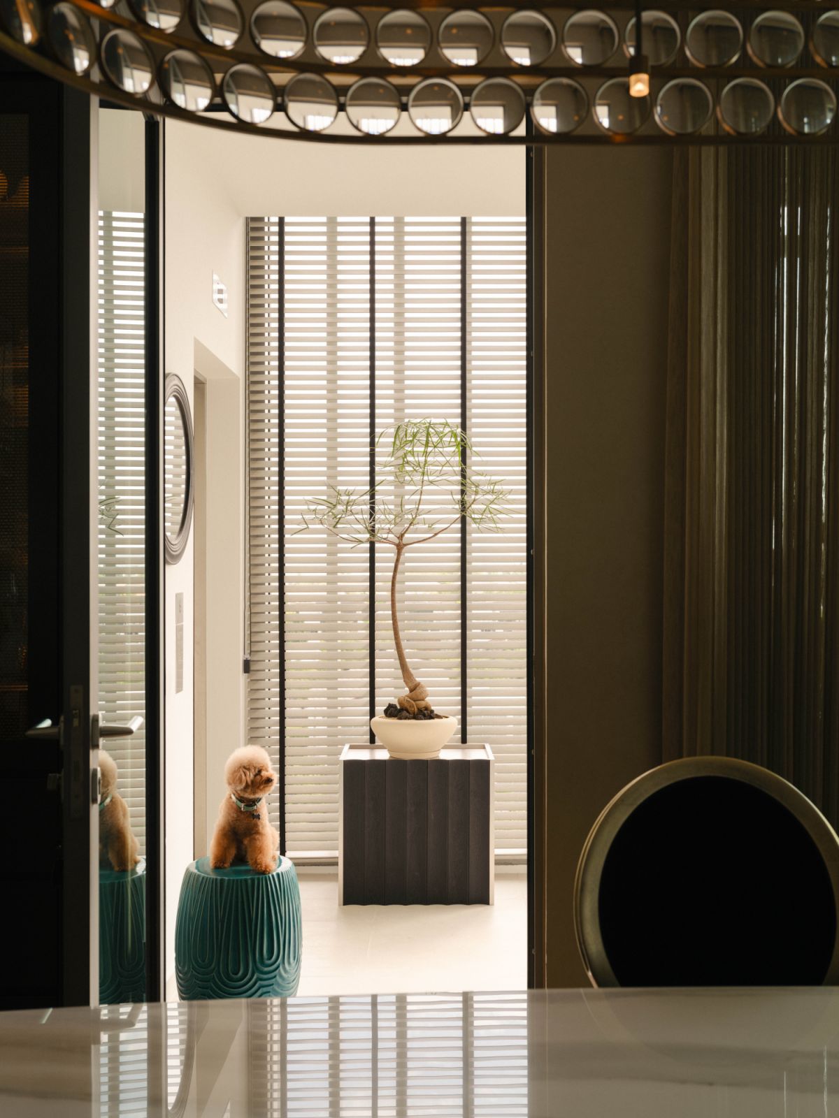Asian elements such as a bonsai plant and ceramic stool create a poetic vignette in the entrance area
