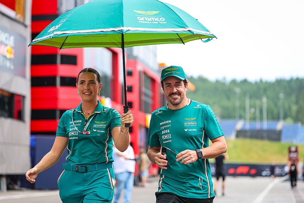 SPIELBERG, AUSTRIA - JUNE 26: Fernando Alonso of Spain and Aston Martin F1 Team and his PR officer seeks shelter with an umbrella as they walk through the paddock in the rain during previews ahead of the F1 Grand Prix of Austria at Red Bull Ring on June 26, 2025 in Spielberg, Austria. (Photo by Kym Illman/Getty Images)
