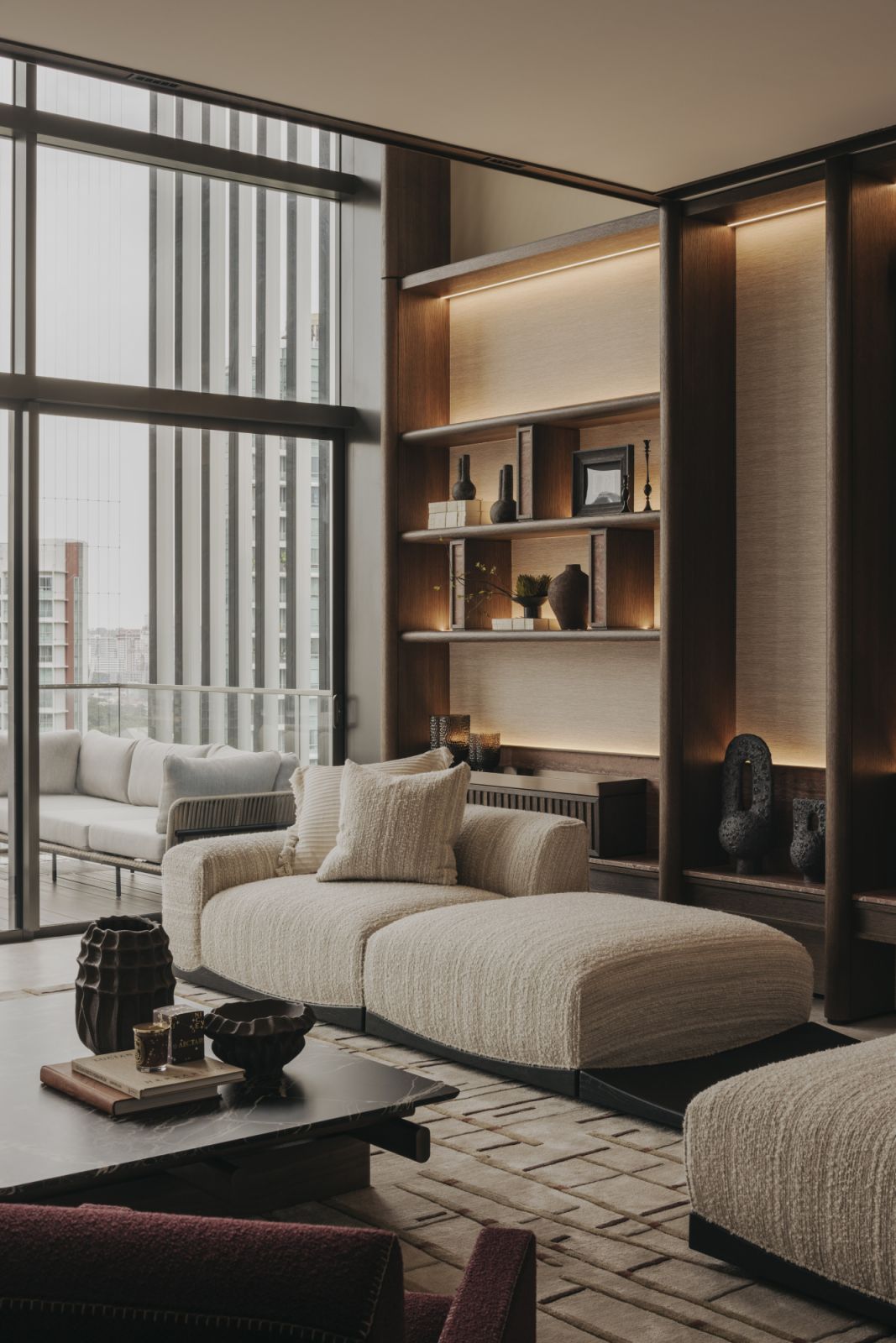 The interiors feature timeless pieces, such as the Cassina Utrecht armchair, and a continuous feature wall connecting the balcony to the living areas
